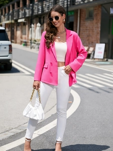Gros plan du blazer croisé rose vif porté avec un haut court blanc et un pantalon blanc chic
