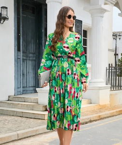 Detail of V-neck printed pleated dress with green abstract pattern and black waist belt