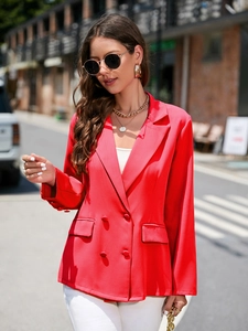 Détail d'un blazer rouge à boutonnage croisé avec col à revers et poche à rabat