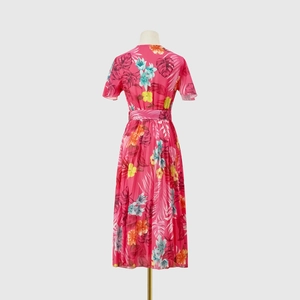 Rear view of pink tropical floral pleated midi dress with short sleeves and waist tie