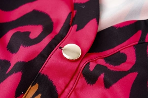 Detail of floral print fabric with a polished gold button on a long-sleeved dress