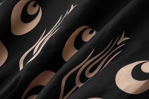 Macro detail of black fabric with beige geometric ethnic patterns and elegant folds