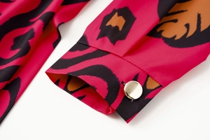 Detailed view of magenta leopard print sleeve with a luxury gold button closure