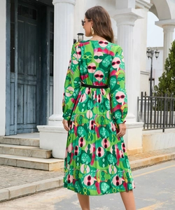 Detail of green pleated dress with fun glasses print and a black belted waistline