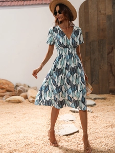 Detail of the V-neck and tropical leaf print on this white short-sleeve midi dress