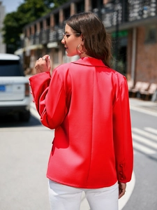 Gros plan du blazer rouge avec épaules structurées et boutons décoratifs sur les manches