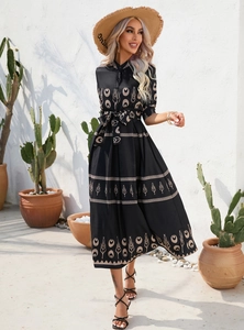 Close-up of the black dress featuring ethnic plant patterns and a tied waist belt detail
