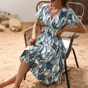 Close-up of V-neck floral summer dress with tropical leaf print and smocked waist detail