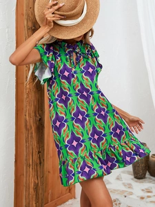 Detail of vibrant green summer dress featuring ruffle hem and floral prints in a sunlit resort