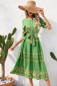 Close-up of green ethnic print dress featuring vintage gold patterns and button closure