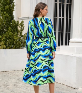 Close-up of long sleeve pleated midi dress with blue and green abstract wave prints