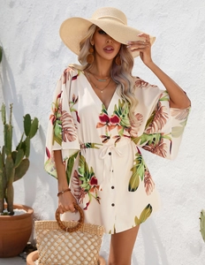 Detail of summer dress featuring tropical leaf print with V-neck and button closure