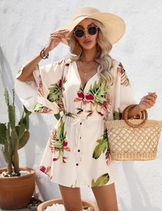 Detail of summer V-neck dress with palm leaf print, drawstring waist, and woven bag