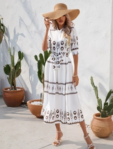 Detail of bohemian geometric pattern on a white midi dress with short sleeves and waist tie