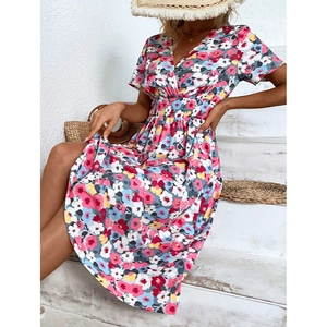 Detail of floral summer dress featuring a V-neck and elastic high waist on a wooden stair
