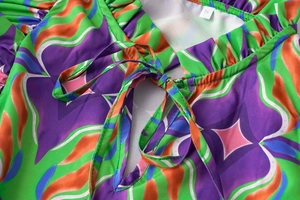 Detail of ruffled V-neck dress with colorful geometric print and tie closure detail