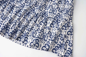 Détail de l'imprimé floral bleu bohème sur tissu blanc avec volants superposés
