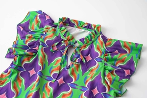 Detail of floral printed top featuring a ruffle collar, neck tie, and flutter sleeves