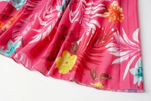 Detail of vibrant tropical floral print and fine pleated texture on pink summer dress
