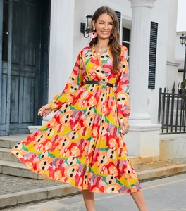 Detailed view of the colorful abstract face print on the long-sleeved pleated dress