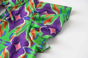 Close-up of vibrant floral print dress detailing ruffle edges and fine stitching quality