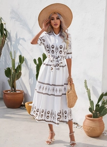 Close-up of white summer dress with brown floral prints and a matching waist belt