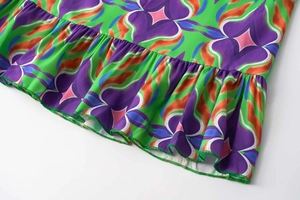 Close-up of vibrant floral print dress showing ruffle hem and neat green overlock stitching