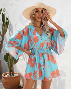 Detail of V-neck floral romper with tropical orange leaf print and drawstring waist