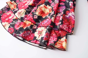 Détail de l'ourlet à volants avec imprimé pivoines éclatant sur tissu noir soyeux