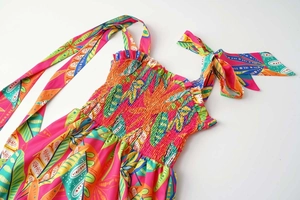 Detail of smocked tube dress with tropical leaf prints and large shoulder bow ties