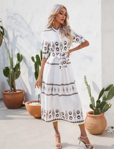 Close-up of white dress featuring floral patterns, stand collar and matching waist belt
