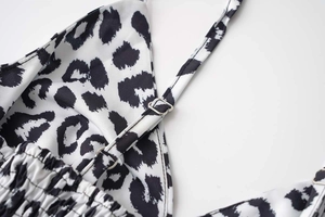 Detail of adjustable thin shoulder straps with silver metal buckles on leopard print dress
