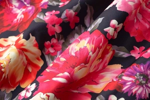 Gros plan sur l'imprimé floral vibrant sur tissu satiné noir lisse avec drapé