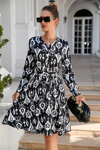 Close-up of black and white abstract print dress with V-neckline and button details