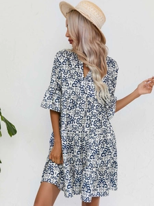 Détail de robe bohème à col en V avec imprimé floral bleu et manches évasées évasées