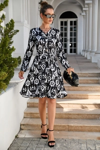 Close-up of V-neckline with decorative buttons and black and white geometric print dress