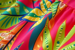 Macro shot of tropical leaf print fabric in vibrant pink and green with fine texture