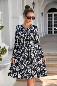 Detail of printed maxi dress featuring a V-neck, waist tie belt and monochrome patterns
