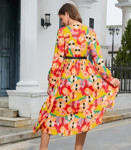 Rear view of pleated V-neck dress featuring colorful abstract face prints and black belt
