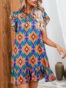 Detail of vibrant geometric print dress featuring ruffled stand collar and tie neckline