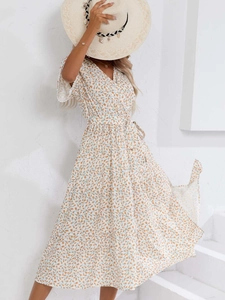 Détail d'une robe fleurie blanche à col en V avec imprimé jaune et ceinture à nouer
