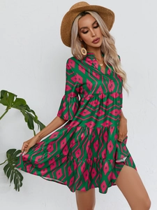 Détail de robe verte à col en V avec imprimé géométrique rose et manches à volants