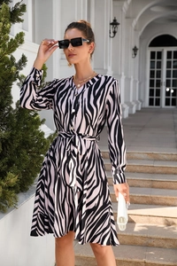 Detailed view of zebra print dress featuring V-neckline, waist tie, and button closure
