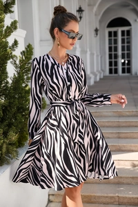 Detail of elegant long-sleeve maxi dress featuring zebra print and a waist tie belt