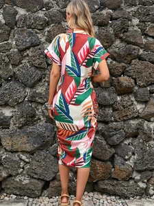 Back view of a midi tropical print dress featuring ruffled side and vibrant leaf patterns