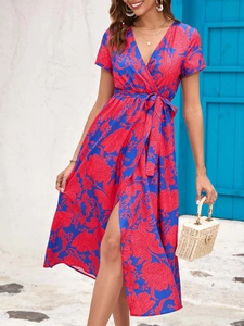 Detail of blue floral wrap dress with V-neck, waist tie, and side slit on model