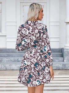 Detail of floral printed mini dress showing long sleeves and ruffled hem on model back
