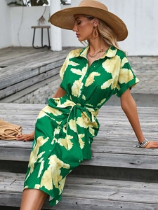 Detail of green floral dress featuring lapel collar, button down front, and waist tie
