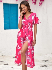 Detail of bohemian floral maxi dress with high slit and palm leaf pattern on pink fabric