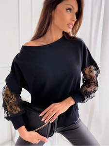 Detail of elegant black long sleeve top with floral lace patchwork and off-shoulder cut
